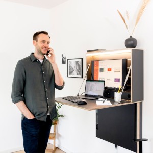 Klappt. Wandschreibtisch anthrazit | stehende Arbeitsposition | aktivierte Frontbeleuchtung Klappt. Wandschreibtisch anthrazit | stehende Arbeitsposition | aktivierte Frontbeleuchtung